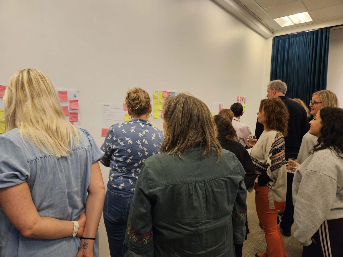 En gruppe mennesker står ved en væg med post-its